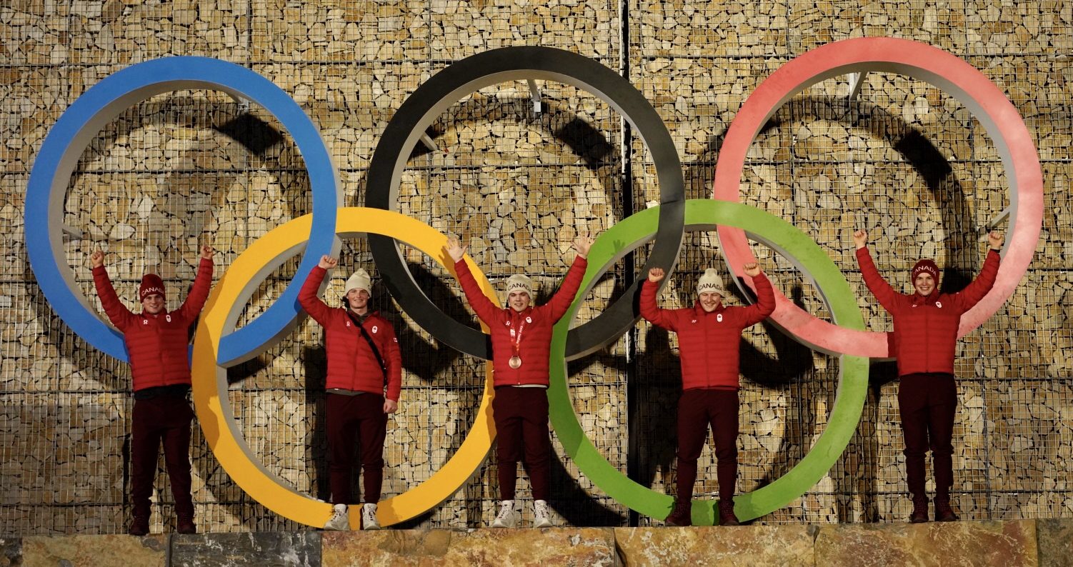 team canada alpine skiers in front of beijing olympic rings